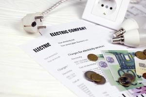 calculadora e notas de euro com caneta na conta de eletricidade europeia. conceito de economizar dinheiro usando lâmpadas led de economia de energia e pagamento de contas elétricas foto