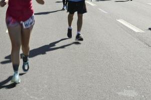corrida de rua, mostrando as pernas de movimento borradas dos corredores foto