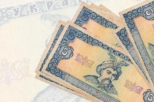 5 contas de hryvnias ucranianas encontram-se na pilha no fundo da grande nota semitransparente. apresentação abstrata da moeda nacional foto
