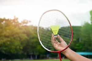 raquete de badminton e petecas de badminton segurando nas mãos para jogar ao ar livre, foco suave e seletivo na corda e raquete, conceito para atividade ao ar livre. foto