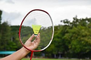 raquete de badminton e petecas de badminton segurando nas mãos para jogar ao ar livre, foco suave e seletivo na corda e raquete, conceito para atividade ao ar livre. foto