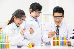 jovens asiáticos sorriem e se divertem enquanto aprendem experimentos científicos em laboratório com professor em sala de aula. estudo com equipamentos científicos e tubos. conceito de educação. foto