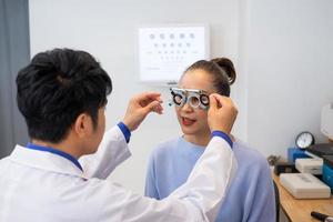 foco seletivo no rosto das mulheres. enquanto médico usando equipamento de optometria e armação de óculos de teste para examinar o sistema visual ocular de mulheres pacientes mais velhas com máquina e técnica profissionais. foto
