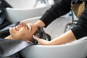 lindas mulheres caucasianas se sentem relaxadas e confortáveis enquanto lavam o cabelo com xampu e massagem. estúdio de cabeleireiro com cabelo elegante, conceito de beleza e moda. foto