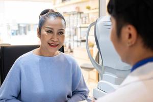 foco seletivo em mulheres pacientes mais velhas enquanto optometrista usando equipamento de refração subjetiva para examinar o olho visual com máquina de optometria profissional antes de fazer óculos. foto