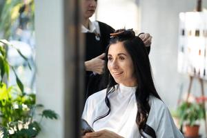 mulheres caucasianas com cabelo elegante enquanto cortam o cabelo e usam máscara facial cirúrgica enquanto estilizam o cabelo para o cliente. ocupação profissional, serviço de beleza e moda novo normal foto