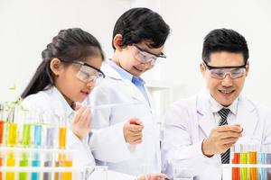 foco seletivo no rosto do menino. jovem menino e menina asiáticos estudam aula de ciências usando microscópio e líquido químico para fazer o experimento dentro do laboratório. conceito de educação. foto