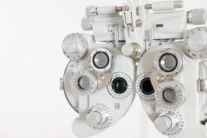 foco seletivo no equipamento de quadro de optometria. com fundo branco desfocado para espaço de cópia. ferramenta optometrista para examinar o sistema visual do olho do paciente com máquina profissional antes dos óculos feitos. foto