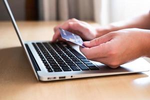 os homens mão segurando o cartão de crédito e digite as informações de pagamento no teclado para fazer compras on-line. tecnologia de internet e conceito de estilo de vida de comércio eletrônico de mercado digital, transação de compra. foto