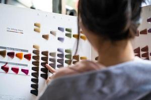 foco na cartela de cores. jovens mulheres asiáticas bonitas sentadas dentro do salão de cabeleireiro, sorrindo enquanto escolhem uma nova cor e estilo de tintura de cabelo na seleção da cartela de cores. moda de beleza feminina, conceito de cuidados pessoais foto