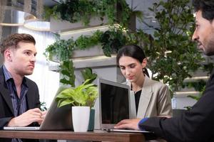 foco seletivo no rosto. grupo de empresários multiétnicos usando laptop, conversando e debatendo dentro do escritório ou espaço de trabalho moderno. reunião corporativa e conceito de discussão de trabalho em equipe. foto