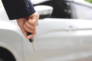 um homem segurando uma chave de carro na frente de um carro em um showroom foto