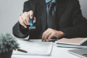 homem carimbando a aprovação de documentos bancários de finanças de trabalho ou de marketing de investimento na mesa. foto