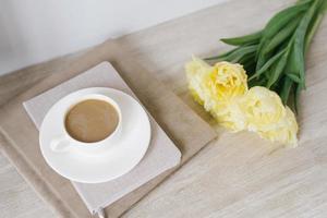 composição criativa de lindas tulipas amarelas delicadas, cadernos e uma xícara de café na área de trabalho de um freelancer ou blogueiro foto