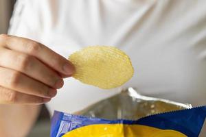 mão segure batatas fritas com saco de lanche foto