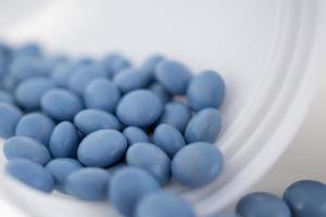 pílulas de remédio azul com garrafa no fundo branco foto