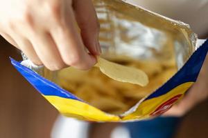 mão segure batatas fritas com saco de lanche foto