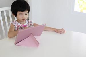 menina asiática jogando tablet digital em casa foto