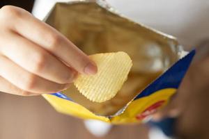 mão segure batatas fritas com saco de lanche foto