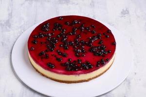 um círculo de cheesecake de mirtilo saboroso em um prato branco sobre uma superfície de mármore branca foto