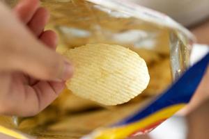 mão segure batatas fritas com saco de lanche foto