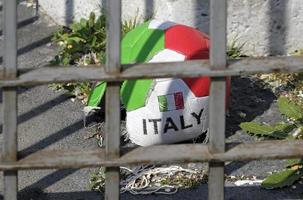 futebol danificado com as cores da Itália atrás de um portão de metal foto