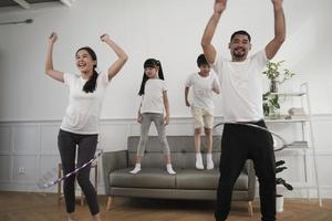 feliz bem-estar família tailandesa asiática, pais e filhos são divertidos jogando bambolê juntos, treinamento físico e exercícios saudáveis na sala de estar branca, estilo de vida doméstico e atividade de fim de semana. foto