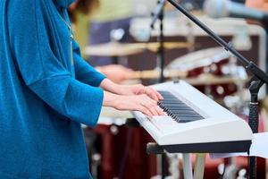 mulher de músico tocando piano de teclado sintetizador, mãos pressionam teclas de sintetizador no palco do concerto foto