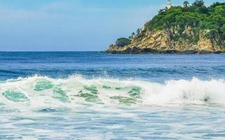 belas ondas de surfista rochas falésias na praia puerto escondido méxico. foto