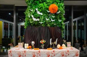 uma foto de halloween em cima da mesa com cabaças caveiras velas pano preto com folhas e morcegos nas costas