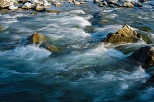 fluxo, para um rio tempestuoso entre as rochas no parque outono em um dia quente
