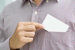 pessoas homem mão segurar cartões de visita mostram maquete de cartão branco em branco. ou frente de exibição de cartão de crédito em papelão. conceito de marca de negócios. foto