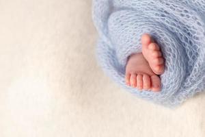 pés de bebê recém-nascido em um fundo de aveia embrulhado em um cobertor de malha foto