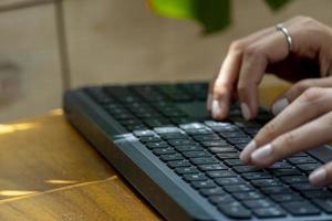 jovem latina mexicana, digitando em um teclado sem fio em seu computador foto
