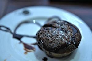 bolo de muffin de chocolate em cima de um prato com calda de chocolate foto