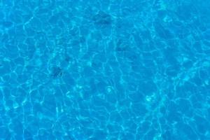 fundo de água na piscina azul, superfície da água com reflexo do sol foto