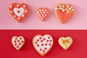 biscoitos decorados em forma de coração em um fundo colorido vermelho e rosa, vista superior foto