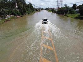 estradas inundadas, pessoas com carros passando. fotografia aérea de drones mostra ruas inundando e carros de pessoas passando, espirrando água. foto