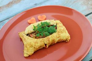 omelete recheado, omelete com salada de legumes e cenoura em forma de coração, em madeira velha azul foto