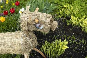 cavalo feito de feno. grama seca. decoração em canteiro de flores. detalhes do jardim. foto