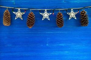 decorações de natal com cones e luzes de natal no fundo azul de madeira, vista superior. foto