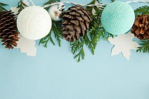 composição plana leiga de natal com ramos de abeto, pinhas, decorações e luzes de natal azuis e brancas sobre fundo azul com espaço de cópia. foto