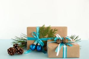 caixas de presente de natal embrulhadas em papel artesanal, fitas azuis e brancas, decoradas com ramos de abeto, pinhas e bolas de natal no fundo azul e branco. copie o espaço. foto