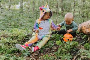 duas crianças andam na floresta com uma cesta de doces de halloween foto