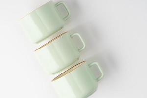 um conjunto de xícaras de cerâmica verde pastel e branco com contornos laranja foto