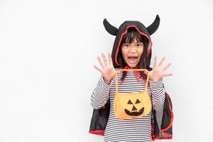 conceito engraçado de criança de halloween, menina bonita com fantasia fantasma de halloween assustador ele segurando fantasma de abóbora laranja na mão, sobre fundo branco foto