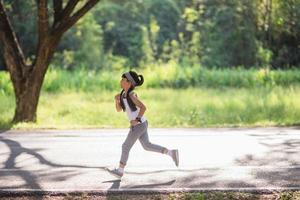 menina criança feliz correndo no parque no verão na natureza. clarão quente da luz solar. pouco asiático está correndo em um parque. esportes ao ar livre e fitness, exercício e aprendizagem de competição para o desenvolvimento infantil. foto