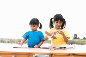 duas crianças brincando com avião de brinquedo de papelão no parque durante o dia. conceito de jogo feliz. criança se divertindo ao ar livre. foto