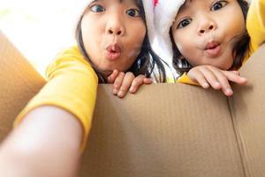 crianças surpresas desembalam a caixa de presente de natal foto
