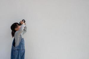 menina asiática olhando através de binóculos em fundo branco. explorar e conceito de aventura. foto